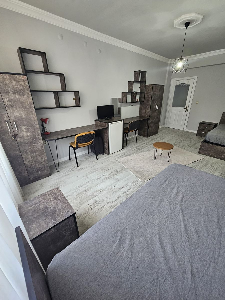 İki kişilik odada iki çalışma masası, mini buzdolabı, TV ve raflar